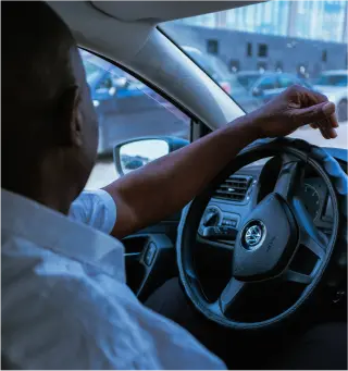 Conducteur dans une voiture, représentant la location de véhicule.